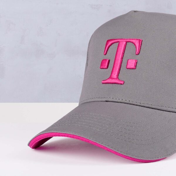 Detailansicht des T Logo-Sticks in Magenta auf der Front der T BASECAP GREY