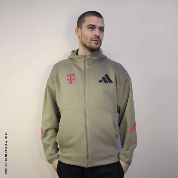 Ein Mann steht vor einem hellen Hintergrund und trägt die ADIDAS T ZIP JACKET UNISEX in hellem Olivgrün, mit magentafarbenen Ärmelakzenten, einem magentafarbenen T-Mobile-Logo und einem schwarzen Adidas-Logo auf der Brust.