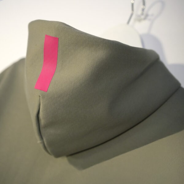 A close-up of the hoodie in the color clay with the hood pulled up and a single vertical magenta stripe near the top.