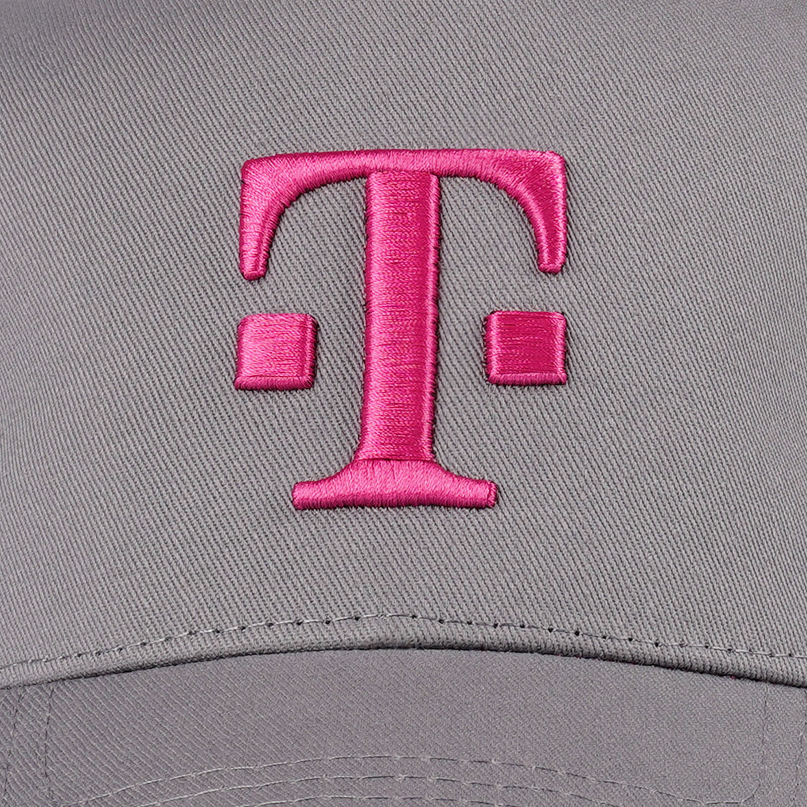 Eine graue Kappe mit einem großen, gestickten, magentafarbenen T-Logo vorne in der Mitte.