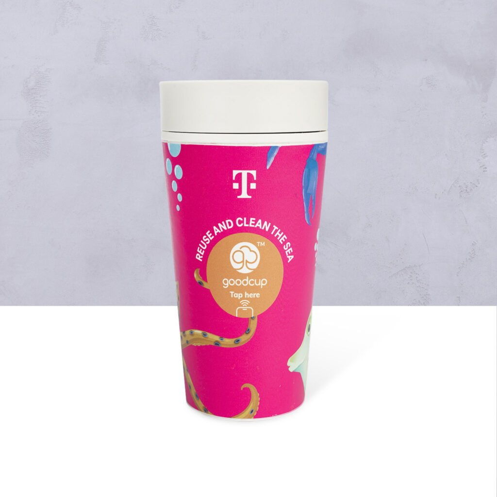 Ein wiederverwendbarer rosa Becher mit einem Meeresmotiv, dem T-Mobile-Logo und dem Schriftzug „REUSE AND CLEAN THE SEA“. Auf der Vorderseite des Bechers sind außerdem das „goodcup“-Logo und der Hinweis „Tap here“ zu sehen.