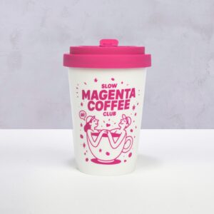 Auf einem weißen Mehrwegbecher mit rosa Deckel sind auf der Vorderseite zwei Menschen in einer Kaffeetasse abgebildet, dazu der Schriftzug „Slow Magenta Coffee Club“. Der Hintergrund ist hellgrau.