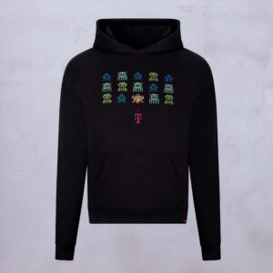 Schwarzer Hoodie mit farbenfrohen, von „Space Invaders“ inspirierten Pixelgrafiken, die in Reihen über die Brust angeordnet sind; darunter befindet sich ein rosa T-Logo. Der Hintergrund ist hellgrau und strukturiert.
