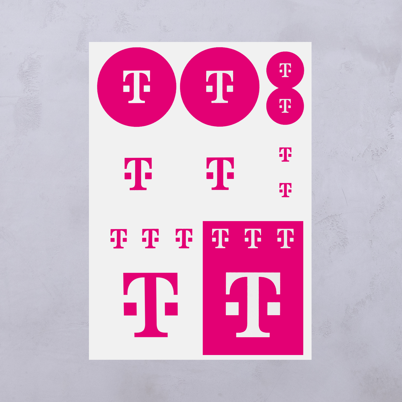 Auf einem weißen Blatt sind verschiedene Größen des magentafarbenen T-Mobile-Logos zu sehen, das aus einem markanten „T“ besteht, das von zwei Quadraten flankiert wird, angeordnet vor verschiedenen kreisförmigen und quadratischen Hintergründen.