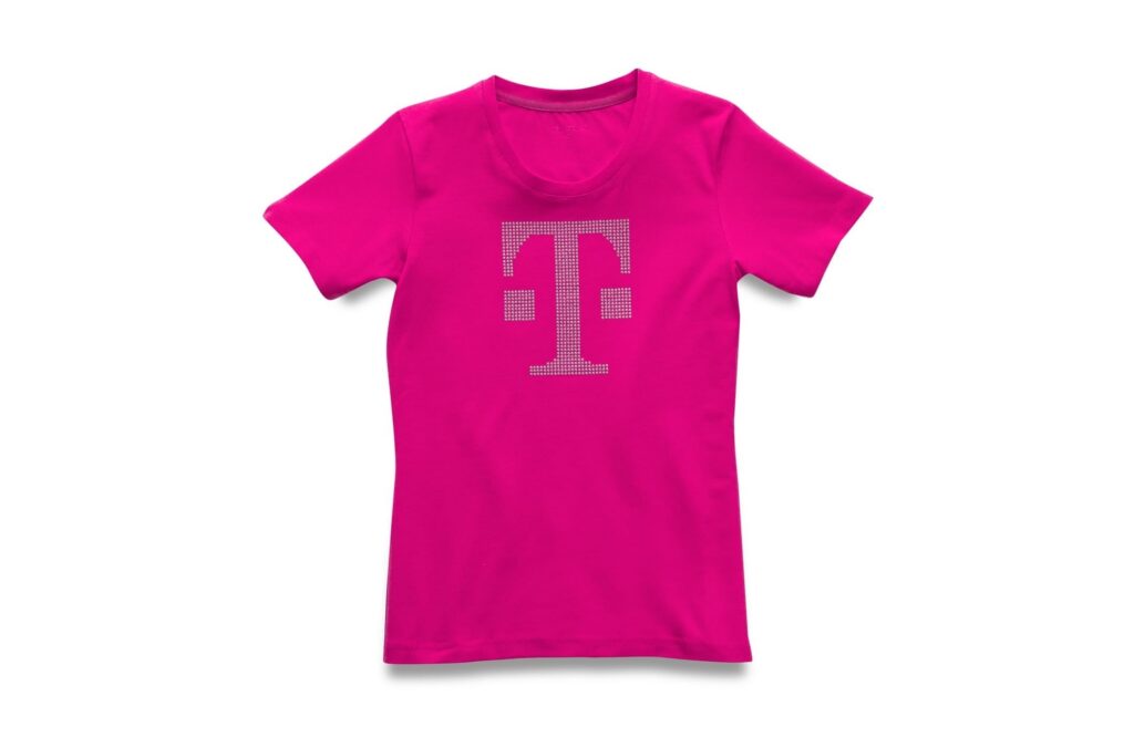Leuchtend pinkfarbenes Kurzarm-T-Shirt mit einem großen, hellen Buchstaben „T“ in der Mitte der Brust. Das Shirt wird vor einem schlichten weißen Hintergrund gezeigt.