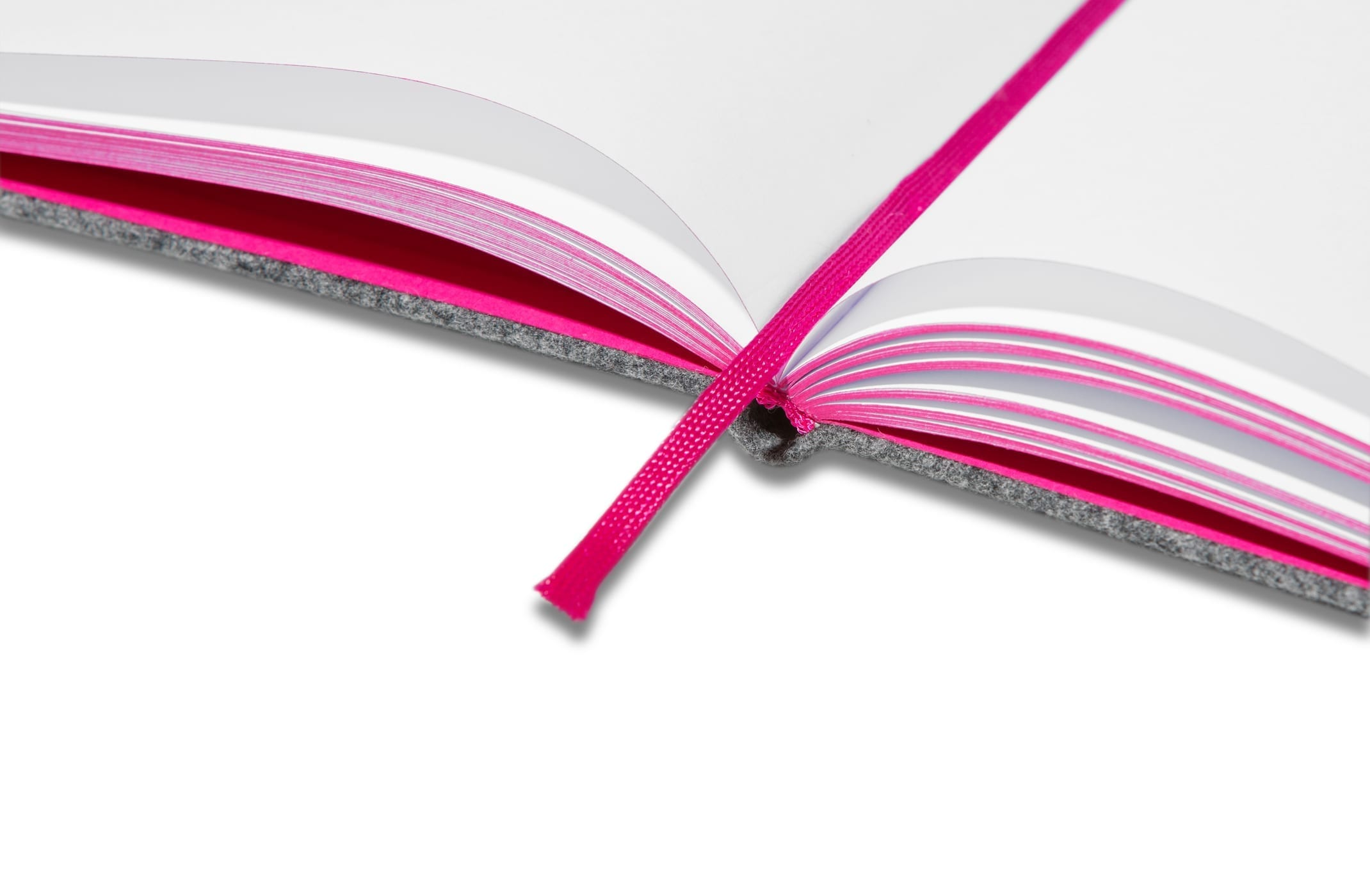 Ein offenes Notizbuch mit leeren weißen Seiten, rosa Seitenrändern und einem passenden rosa Lesezeichenband, das quer über die Mitte verläuft. Der Einband des Notizbuchs ist grau.