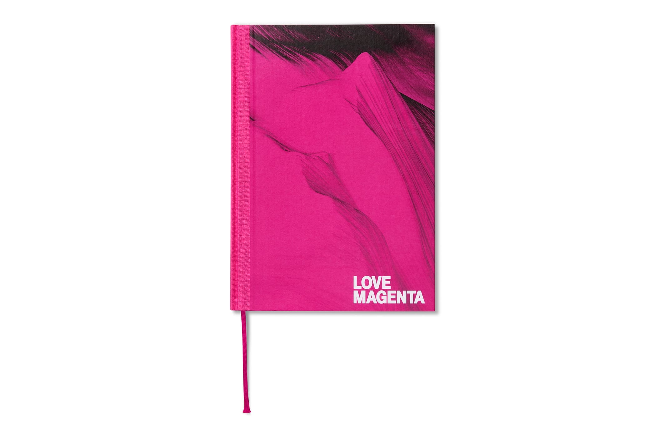 Ein leuchtend magentafarbenes Notizbuch mit festem Einband, das mit abstrakten dunklen Akzenten verziert ist und in der rechten unteren Ecke den weißen Schriftzug „LOVE MAGENTA“ trägt. Ein passendes magentafarbenes Lesezeichenband ist angebracht.