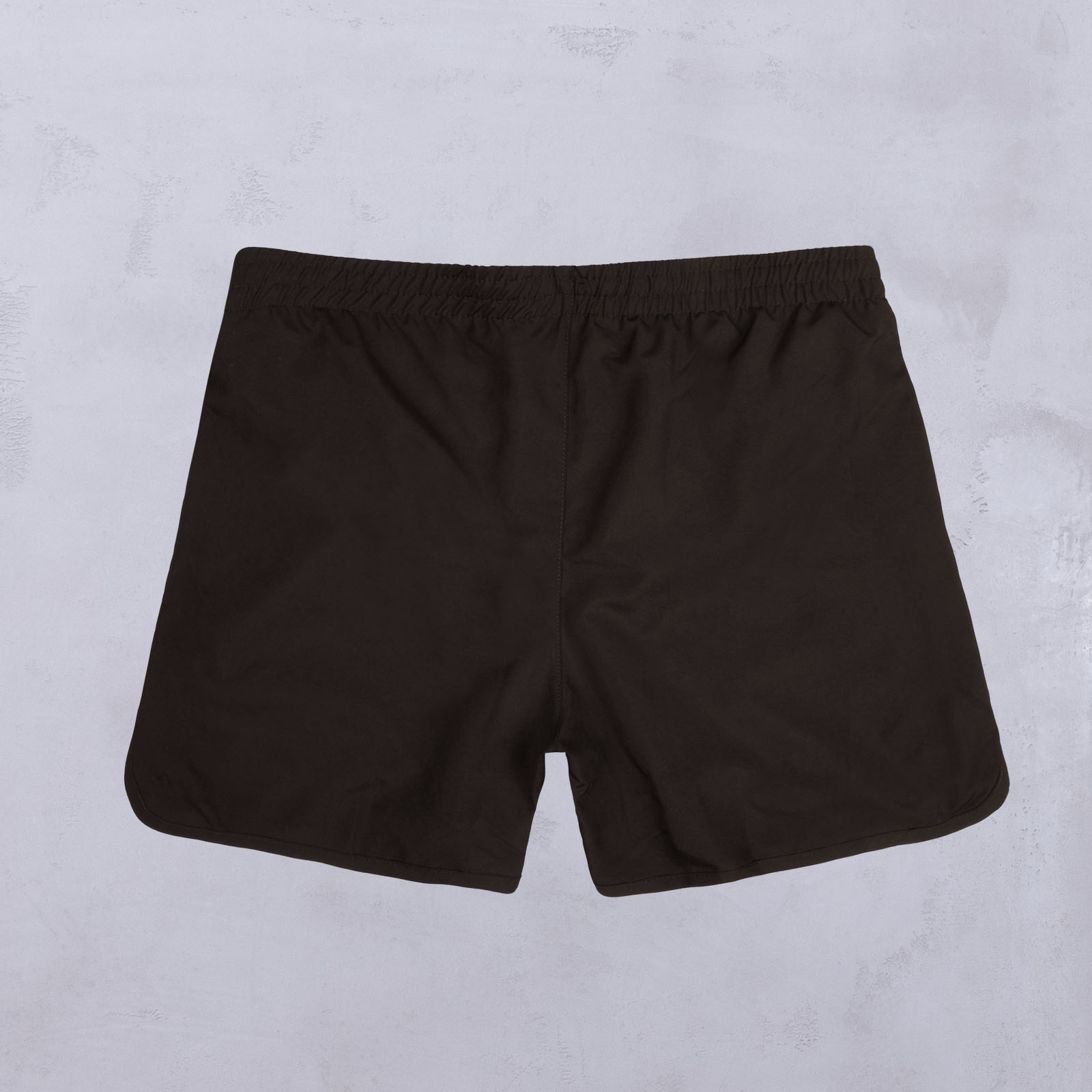 Ein Paar schlichte schwarze Shorts mit elastischem Bund, flach auf einer hellgrauen Unterlage liegend, von hinten gesehen.