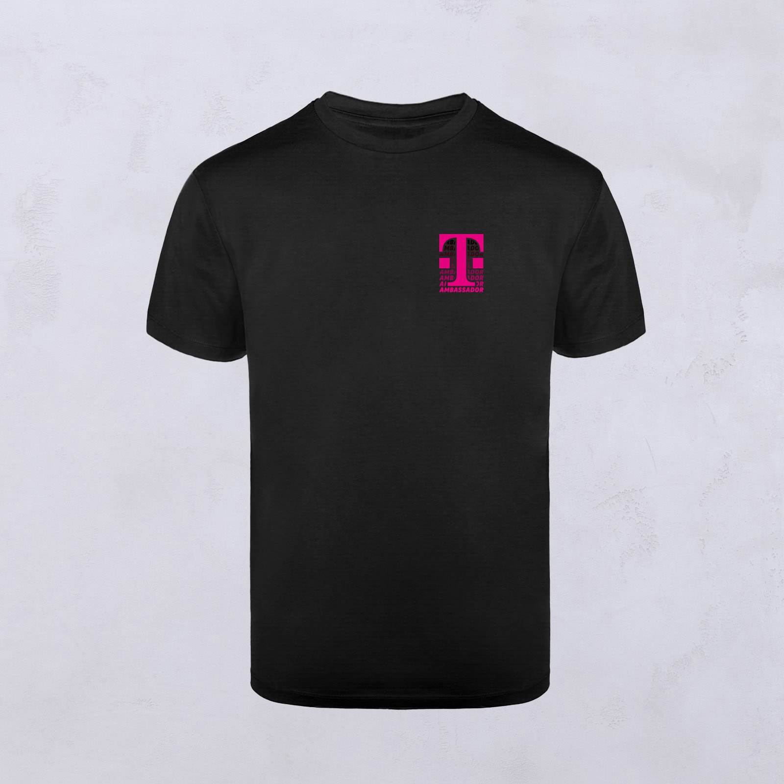 Schwarzes T-Shirt mit einem kleinen, leuchtend pinkfarbenen T-Logo auf der linken Brustseite, das sich von einem hellgrauen, strukturierten Hintergrund abhebt.