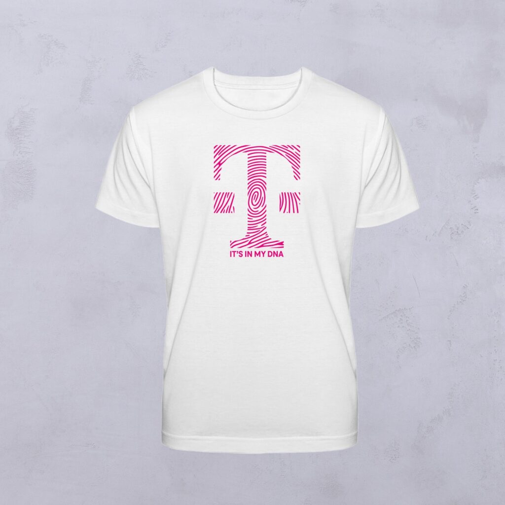Weißes T-Shirt mit einem großen, rosa gemusterten Buchstaben „T“ und dem Schriftzug „ITS IN MY DNA“ in Rosa darunter, verziert mit „Euer Motiv“, vor einem hellgrauen Hintergrund.