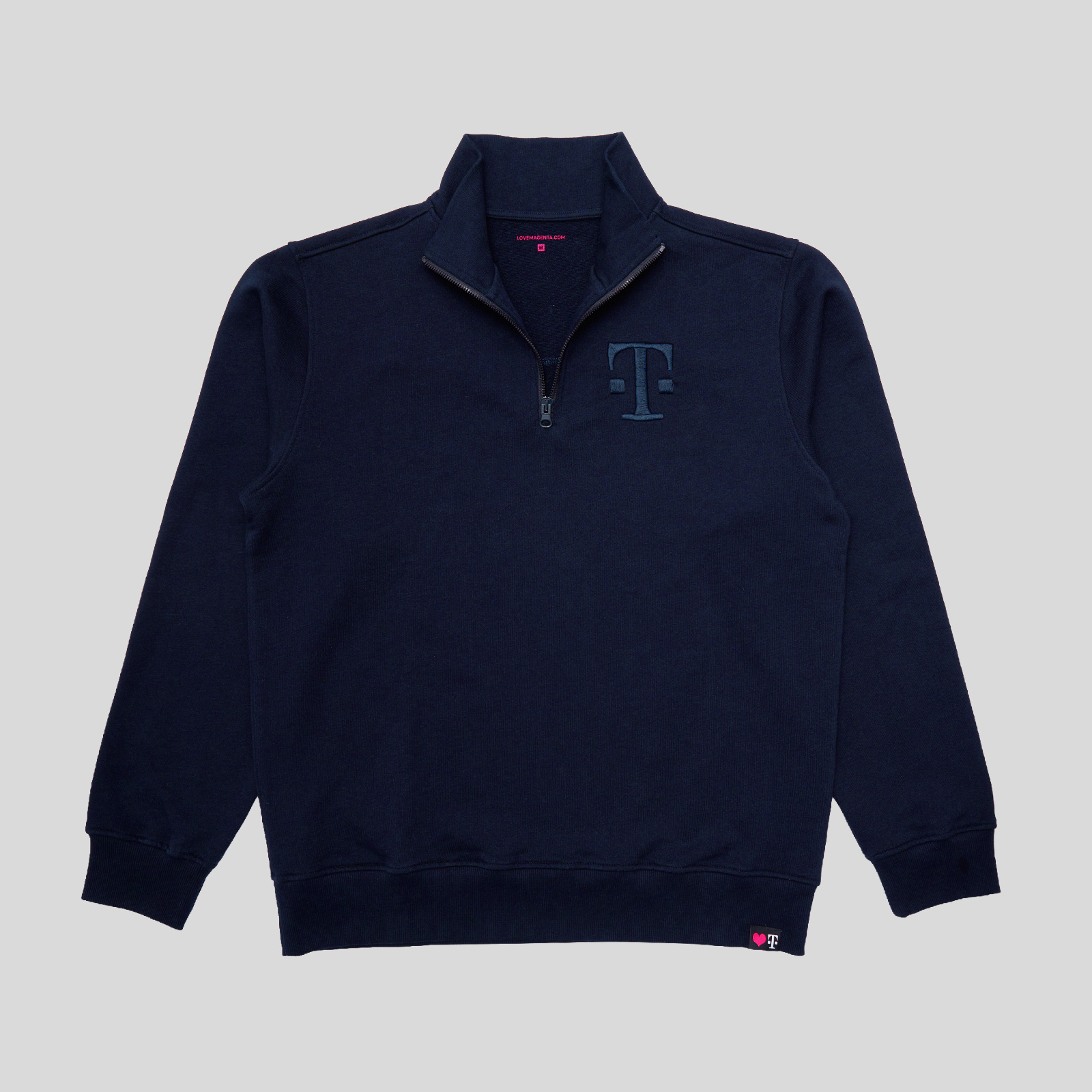Marineblaues Sweatshirt mit Viertelreißverschluss, hohem Kragen und einem T-Logo auf der linken Brust. Das Kleidungsstück liegt flach auf einem einfarbigen hellgrauen Hintergrund.