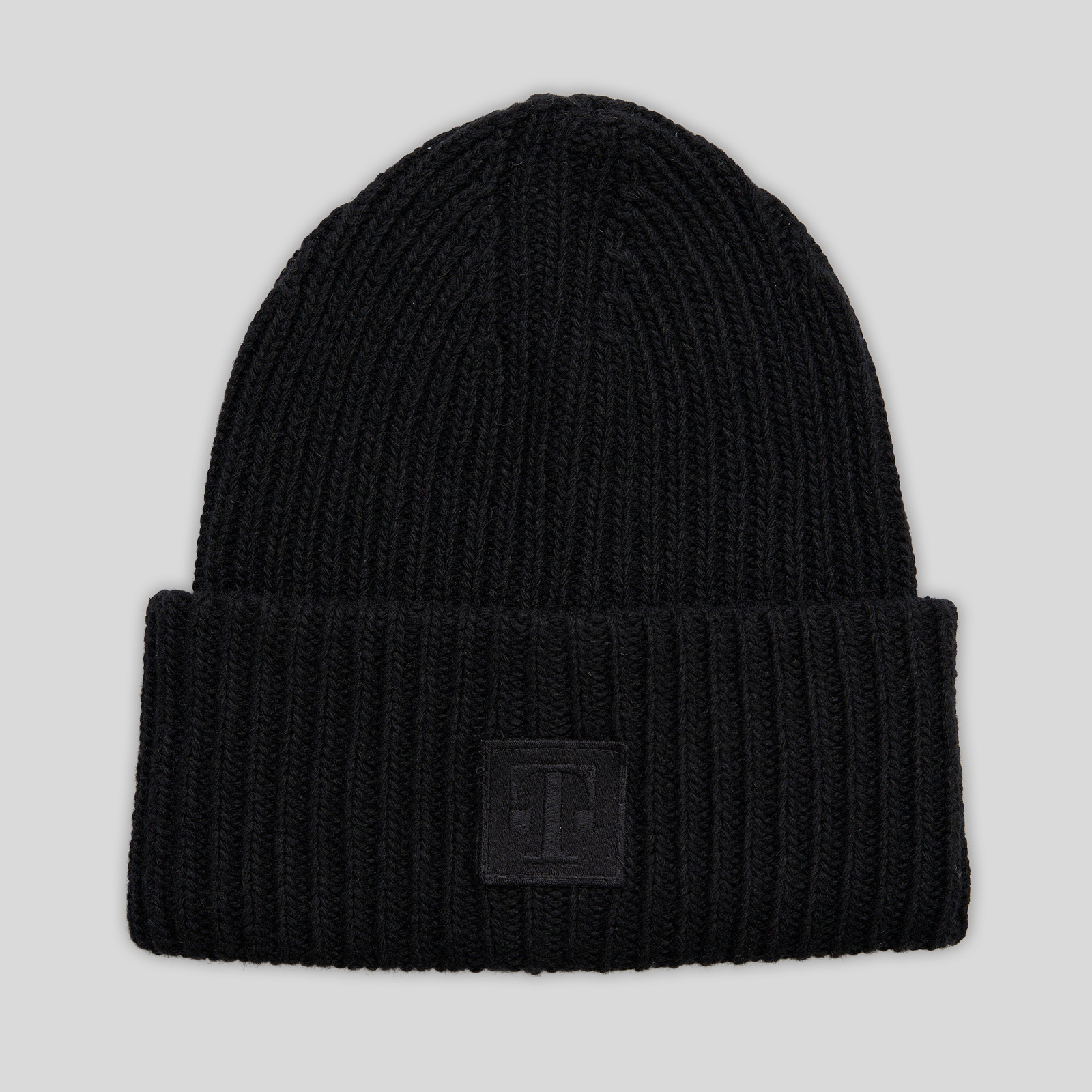 Frontansicht der LOGO BEANIE BLACK aus schwarzem Grobstrick mit breitem Umschlag und gesticktem T-Logo-Patch