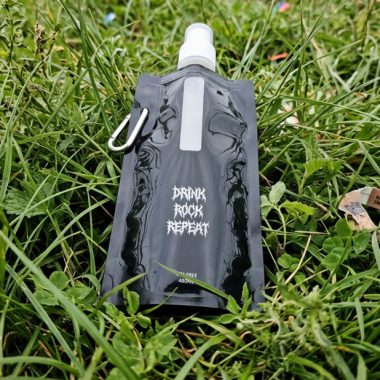 A black reusable water bottle featuring “DRINK ROCK REPEAT” in white lettering on a green background with magenta accents, a 480 ml capacity, a clip, and a cap.